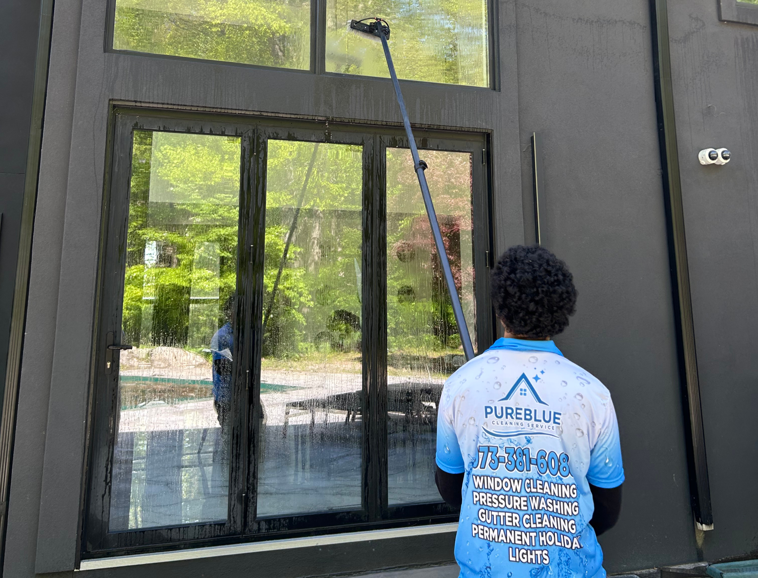 Professional window cleaner in blue cap working on house windows