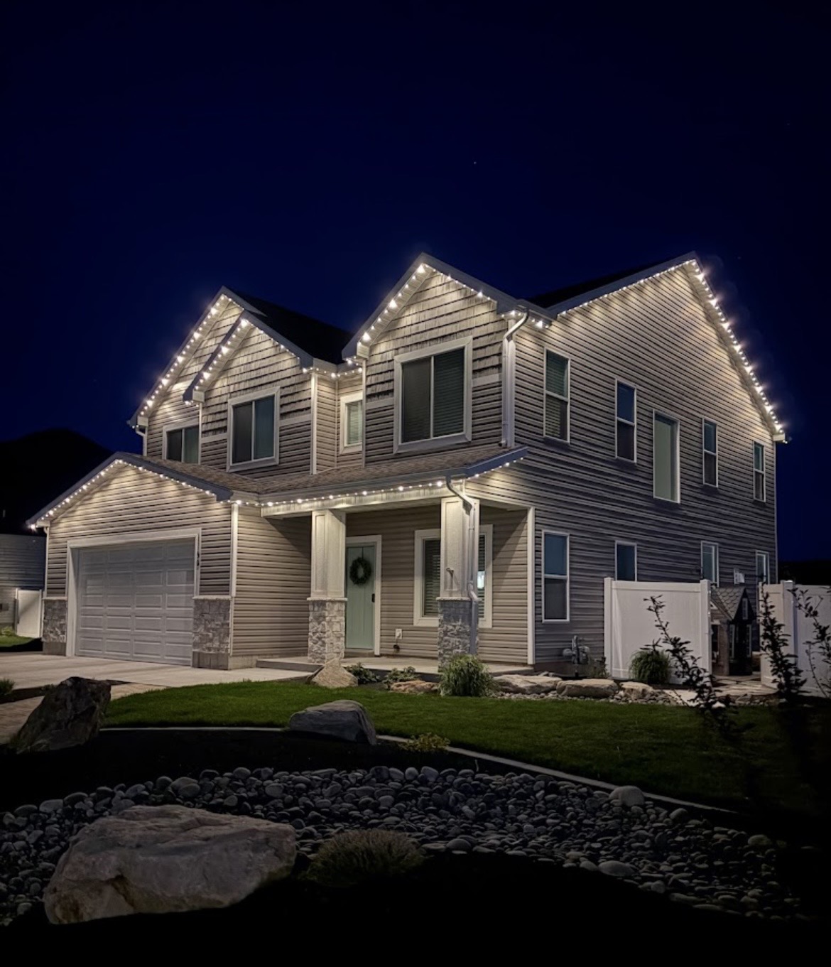 Warm-white permanent roofline lighting installed on a gabled residential home